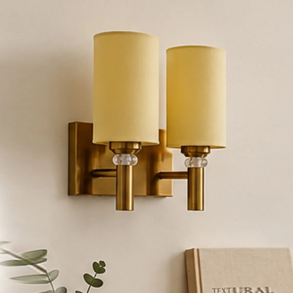 Angled view of the Aurelle twin-shade gold-toned wall lamp