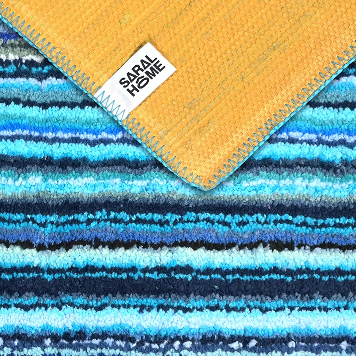 Back of the blue carpet showing its contrasting backing and stitched edge