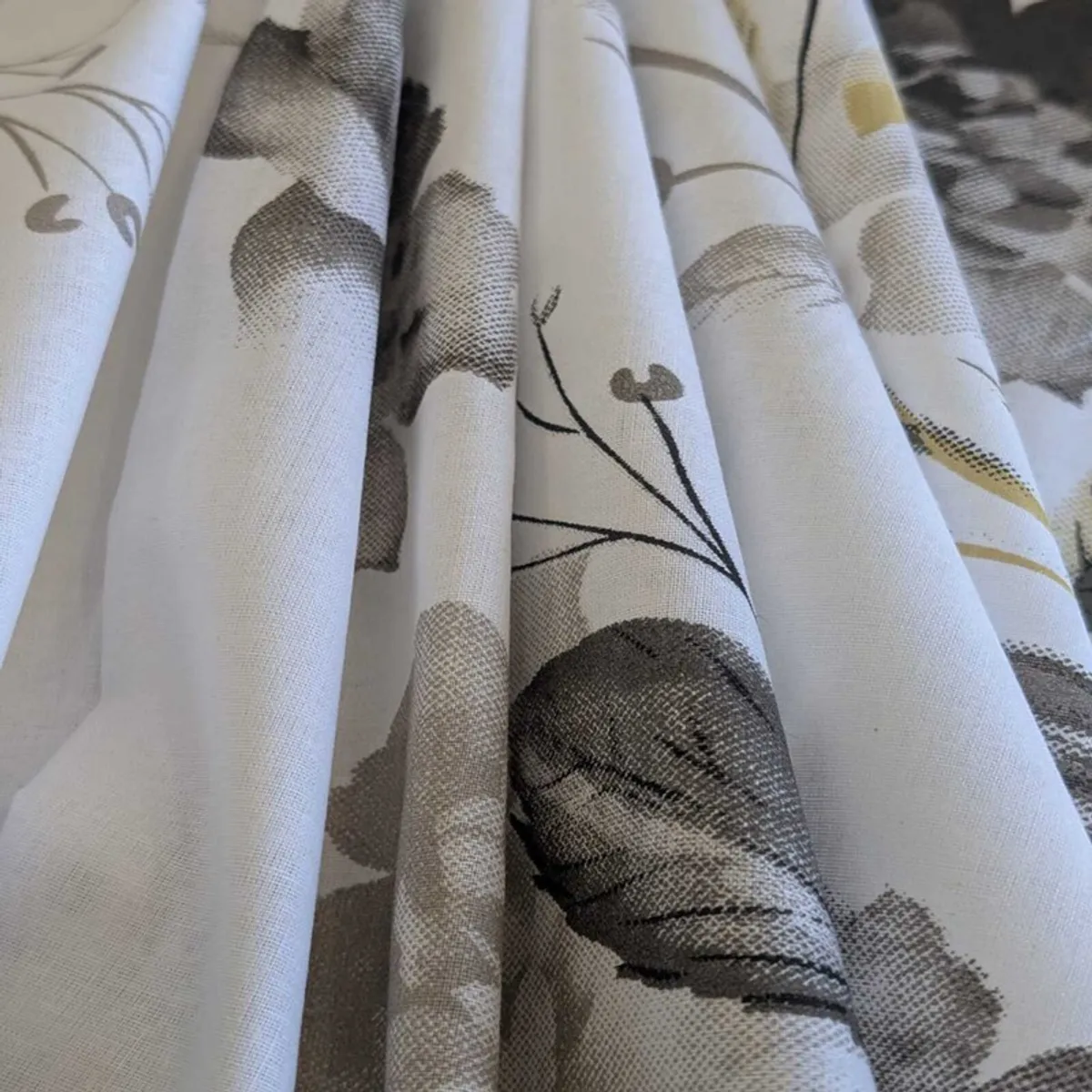 Close-up of floral bedsheet fabric showing grey, black and gold-toned details