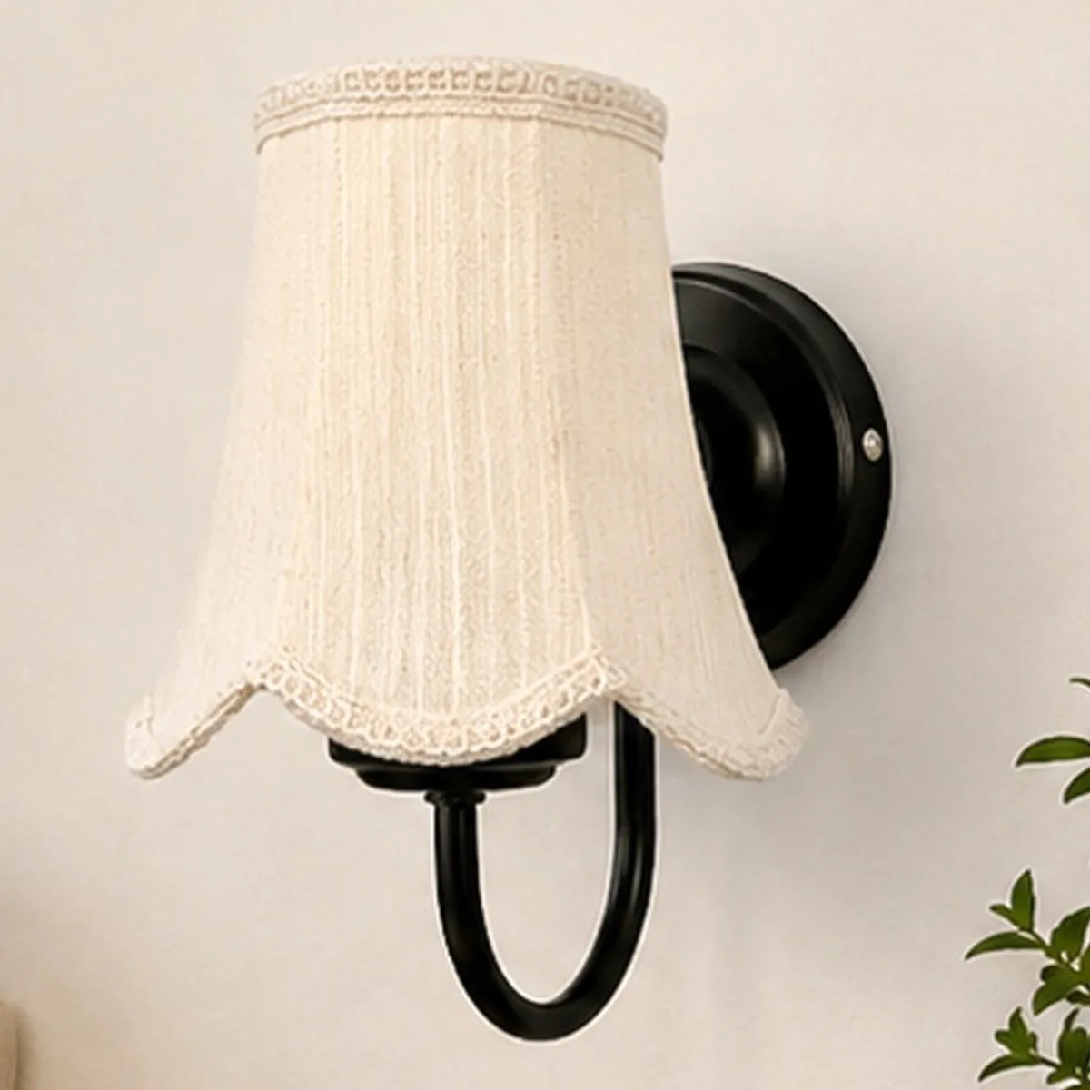 Front view of a white scalloped cotton shade on a black wall lamp