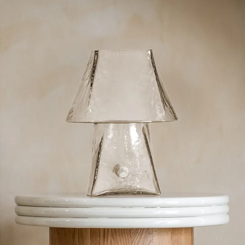 Sculptural clear glass table lamp on a round pedestal table