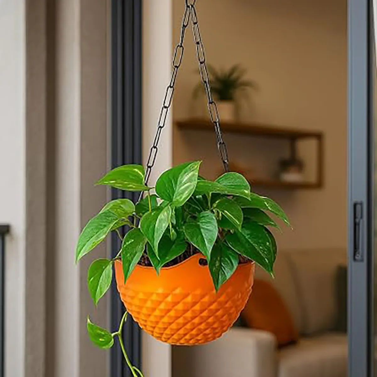 Orange textured hanging planter holding a leafy green plant indoors.