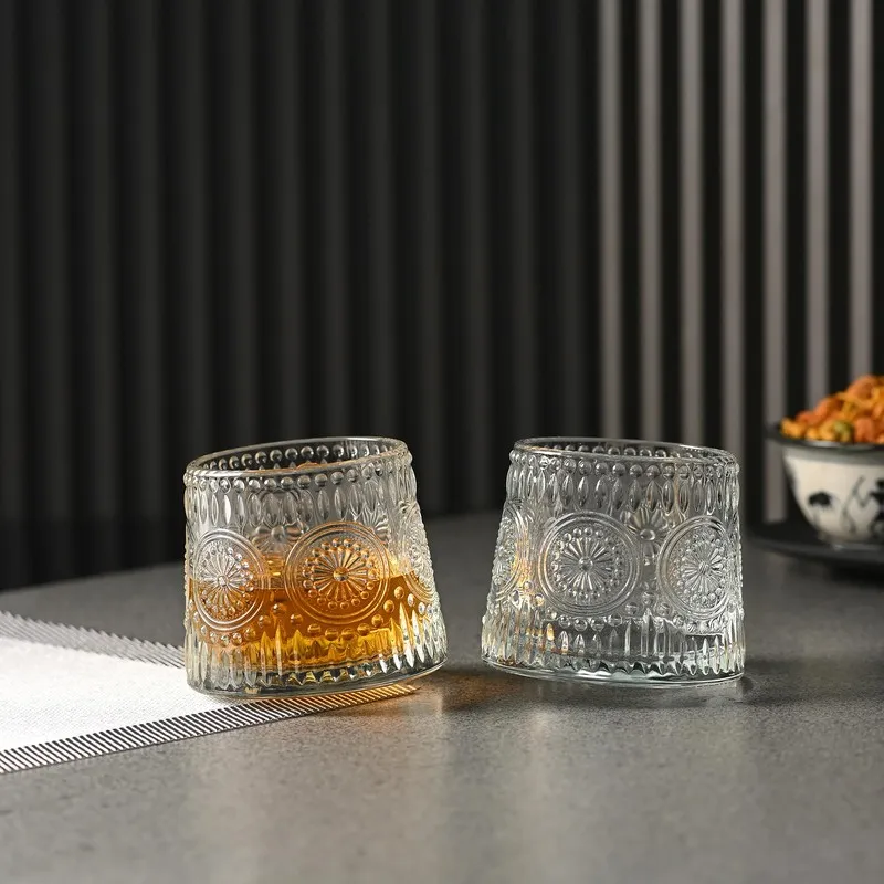 Two clear textured whiskey glasses on a tabletop