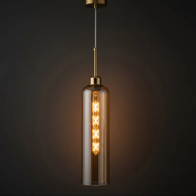 Close-up of amber cylindrical glass pendant lamp with glowing bulb