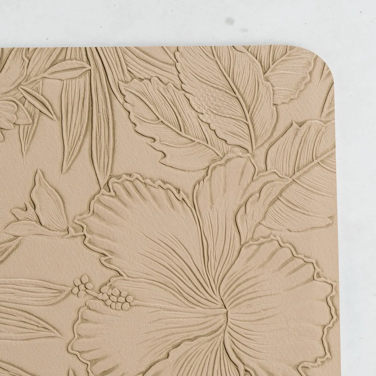 Close-up of the embossed floral pattern on a beige table mat