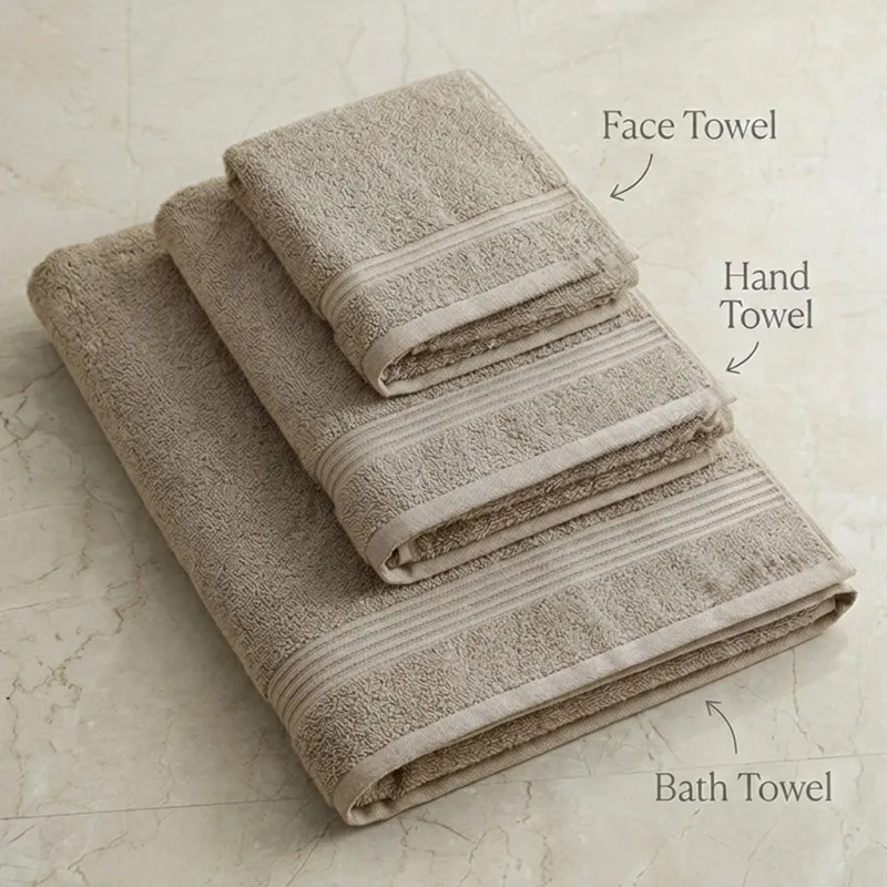 Folded beige face, hand and bath towels with woven border detailing