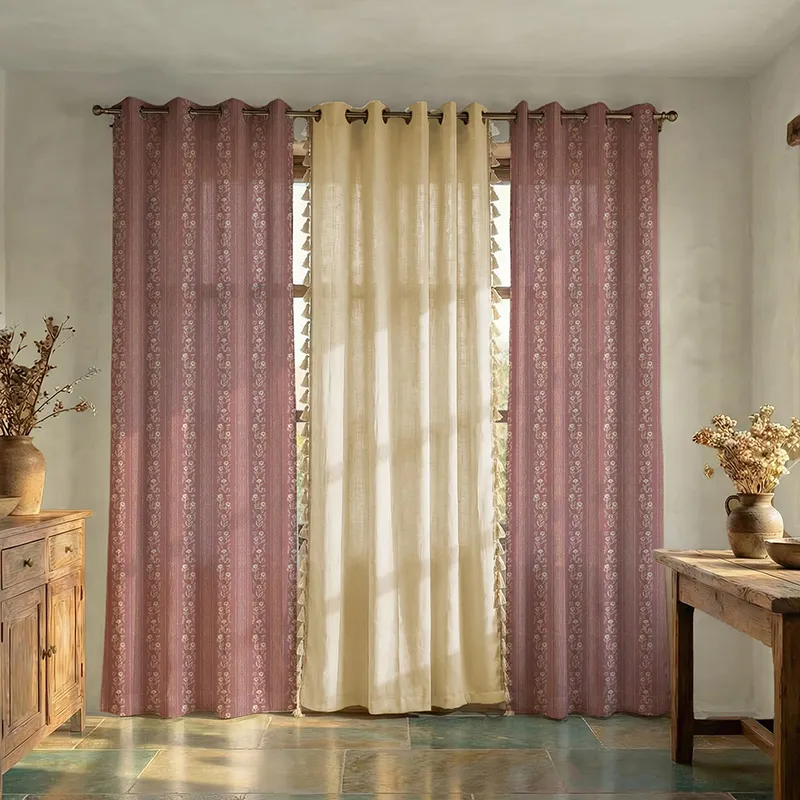 Set of pink and off-white curtains with floral print and tasselled edges on a window