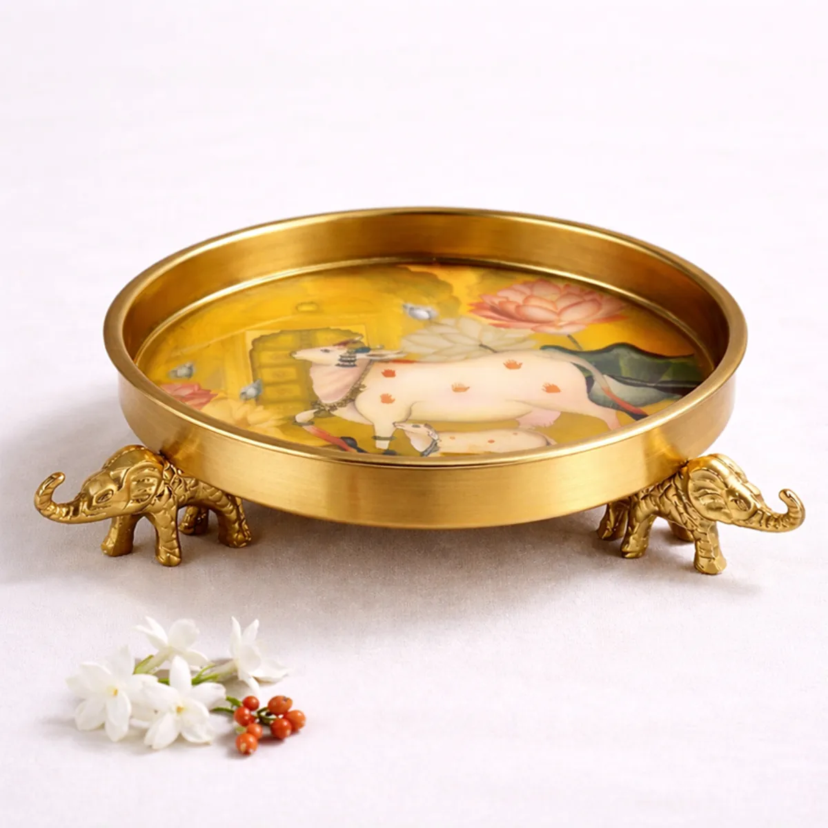 Close view of a round gold Urli with colourful floral artwork and elephant bases