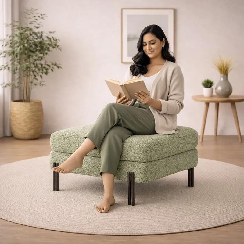 Woman seated on a sage-green bouclé ottoman in a living room
