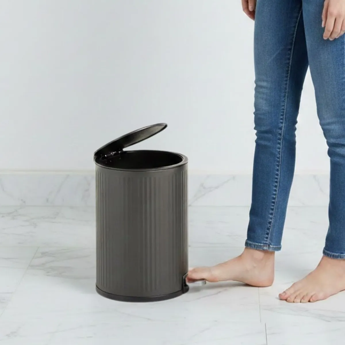 Grey pedal dustbin shown with lid open beside a person