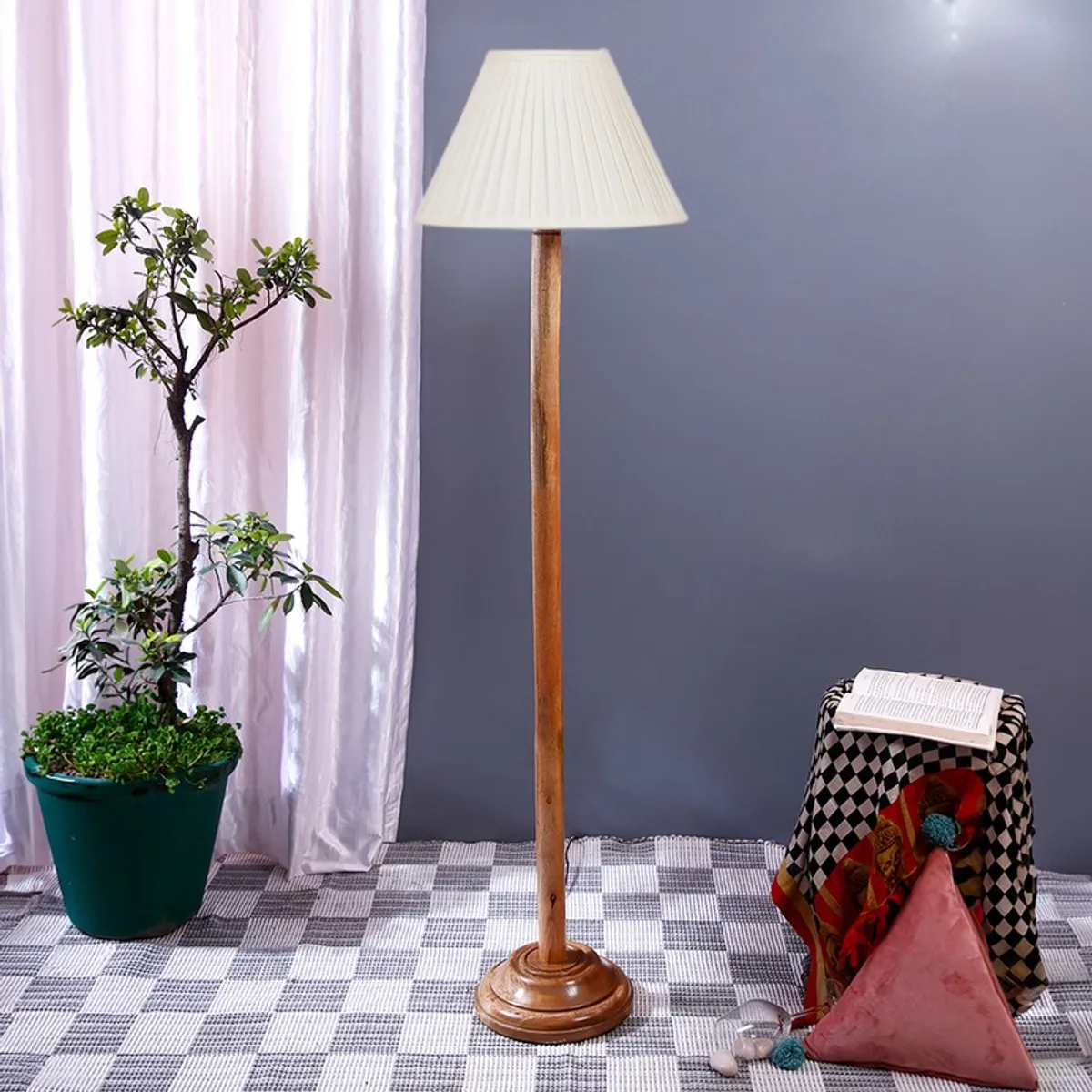 Wooden floor lamp with white pleated shade in a styled room corner