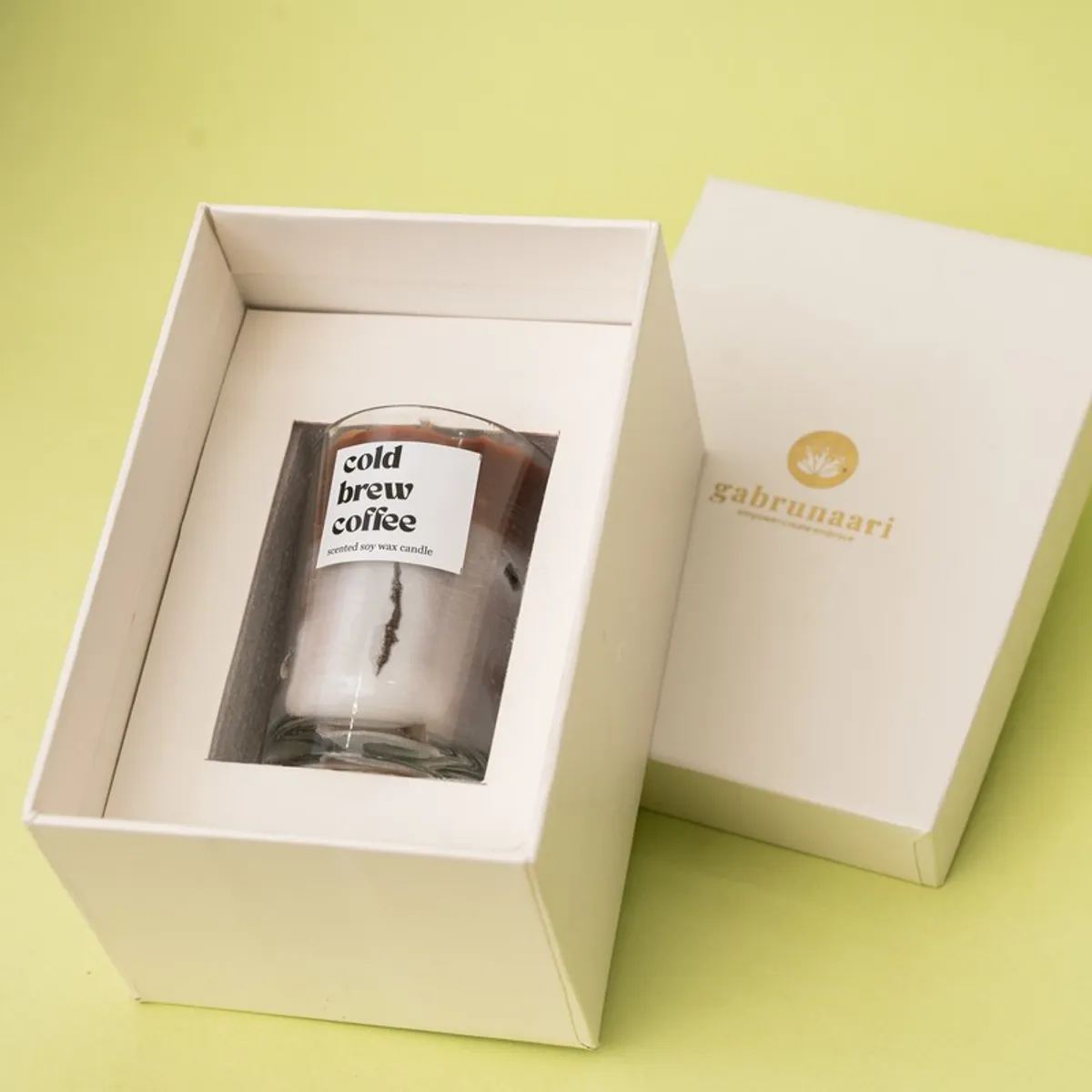Open cream presentation box showing a brown coffee candle in a glass jar