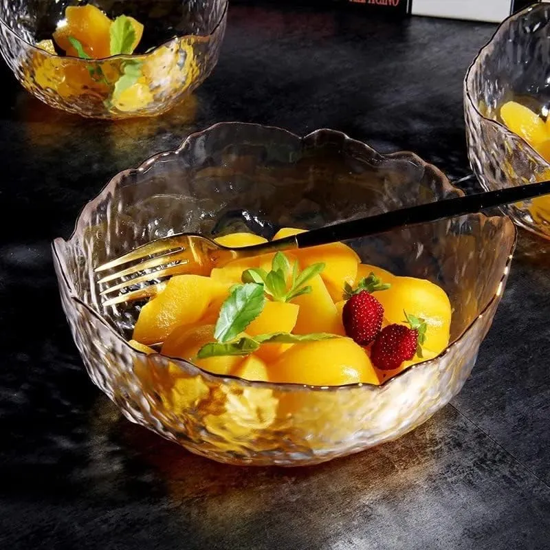 Transparent textured glass bowl filled with colourful fruit on a dark table