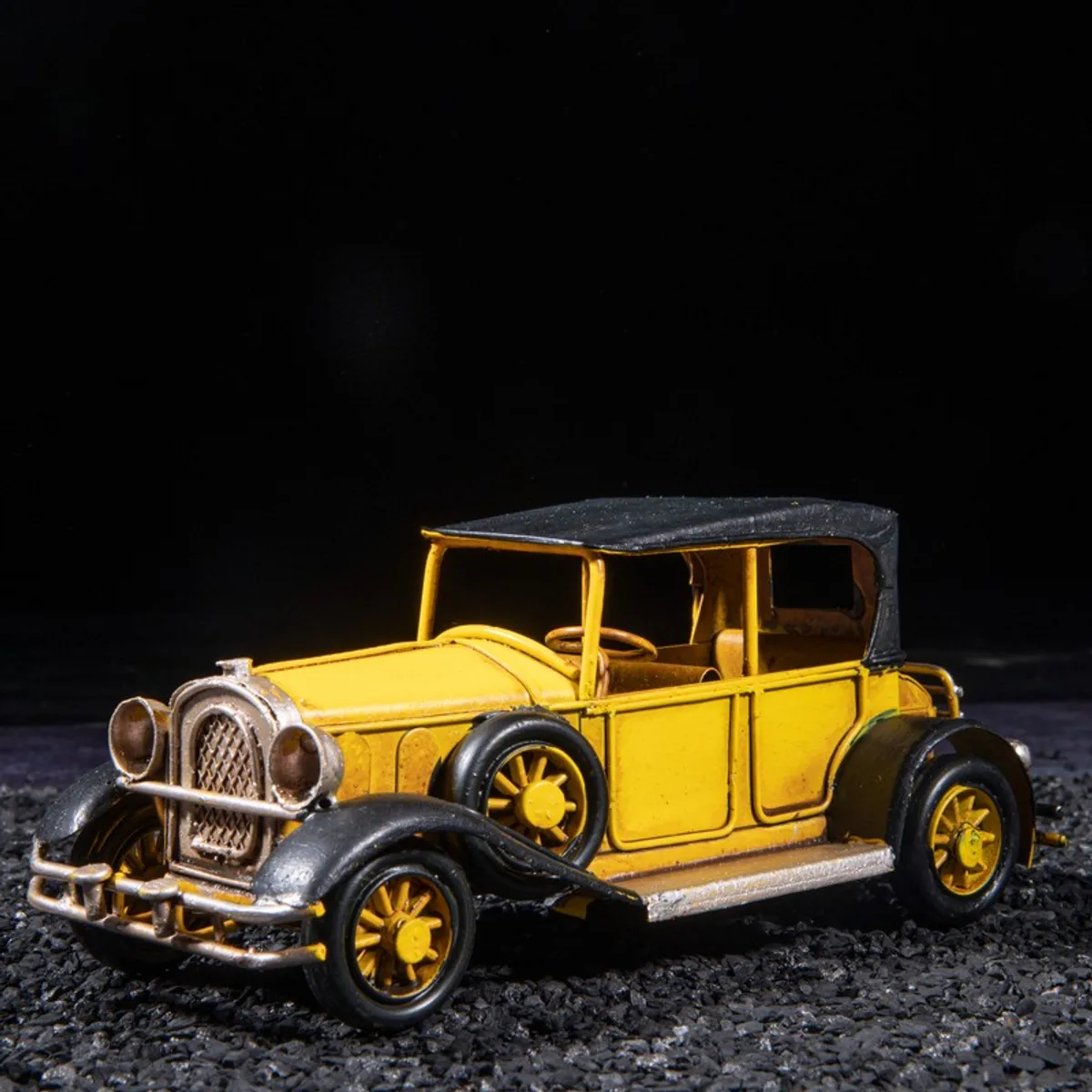 Front angled view of a yellow vintage iron model car showpiece