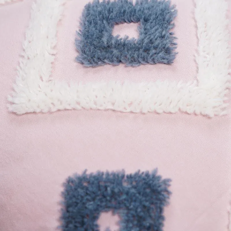 Close-up of the tufted grey and white diamond detailing on pink fabric