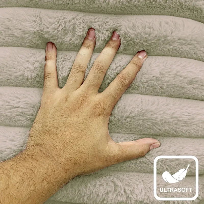 Hand resting on the pale grey plush striped cushion cover texture.