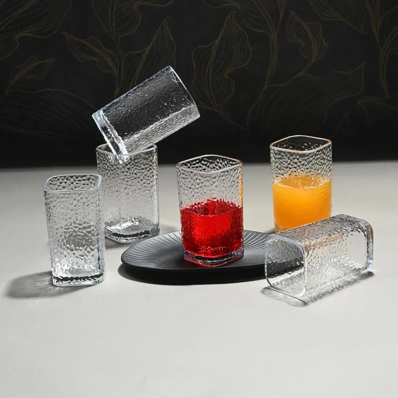 Six textured clear drinking glasses, two filled with coloured drinks