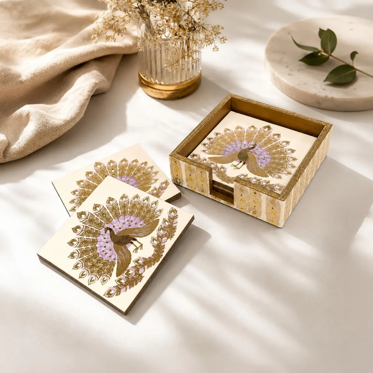 Five peacock coasters arranged beside a decorative storage box