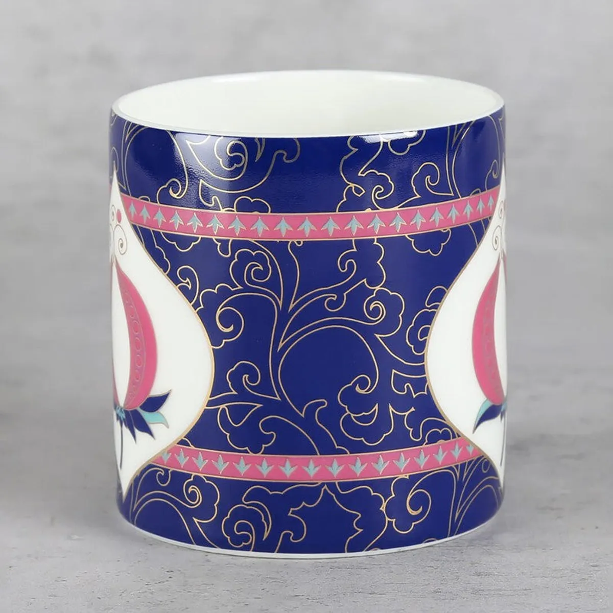 Side view of a blue mug with pink bands and decorative white motif
