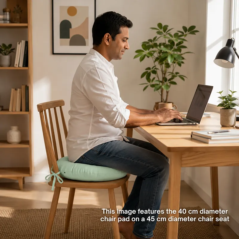 Person seated on a wooden chair with a sage green chair pad