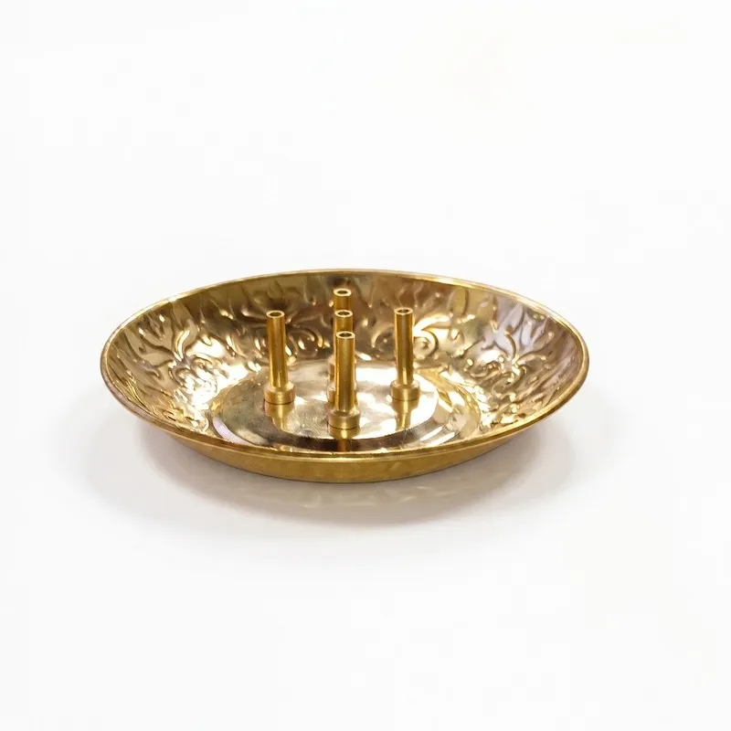 Side view of a shallow round brass incense holder with raised stick holders