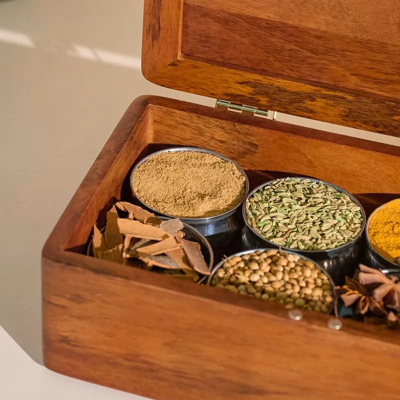 Close view of spices arranged inside an open brown wooden masala box