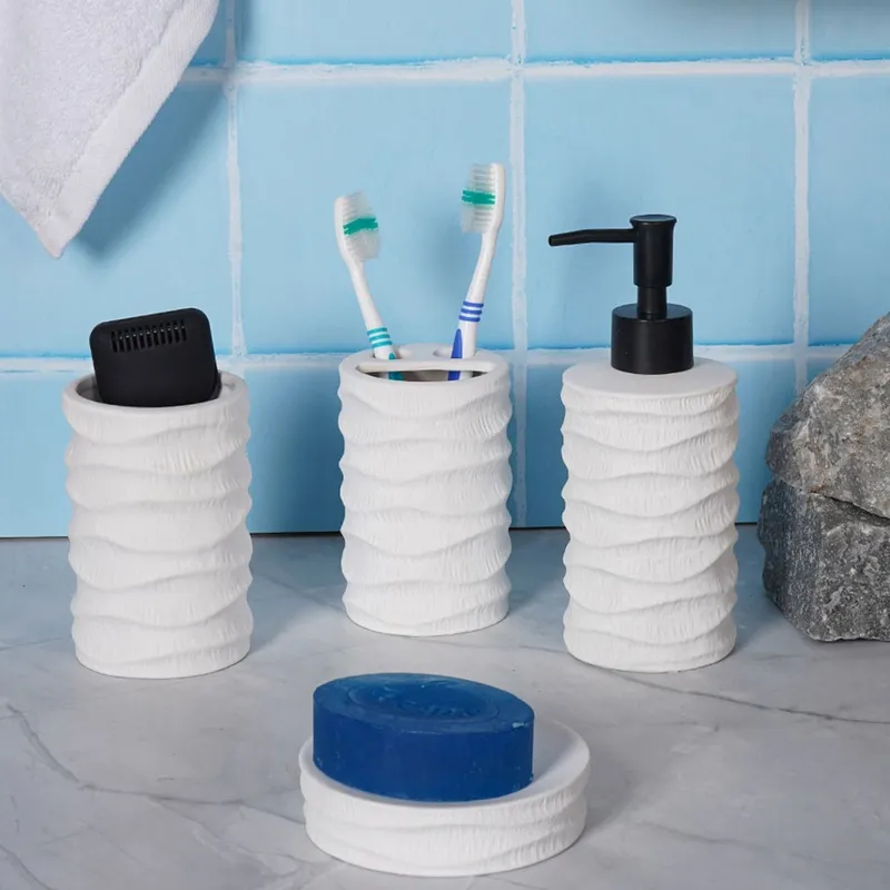 White four-piece bathroom set styled against blue tiles with black soap dispenser pump