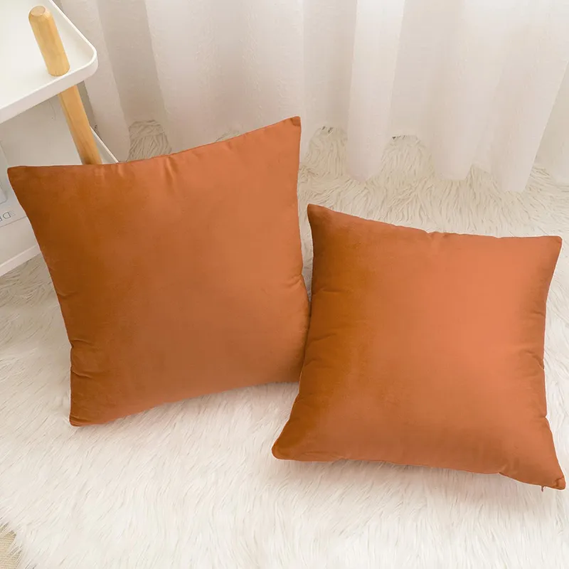 Two rust square cushion covers on a white textured rug