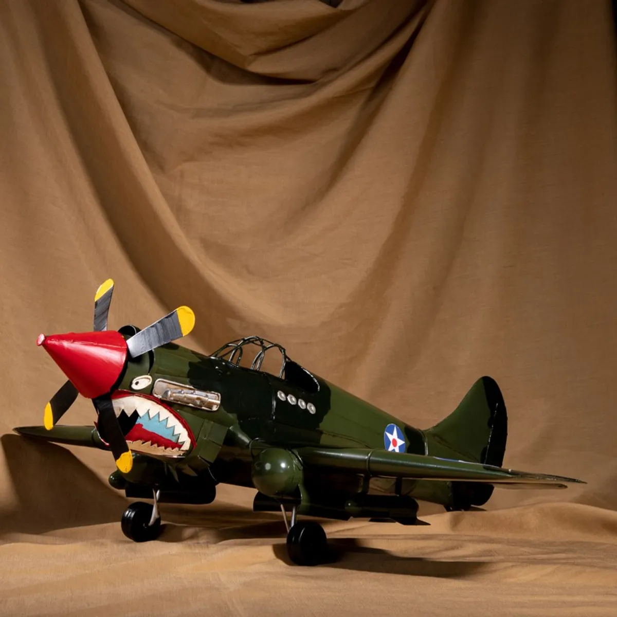 Side view of olive green fighter plane showpiece with shark-mouth detailing