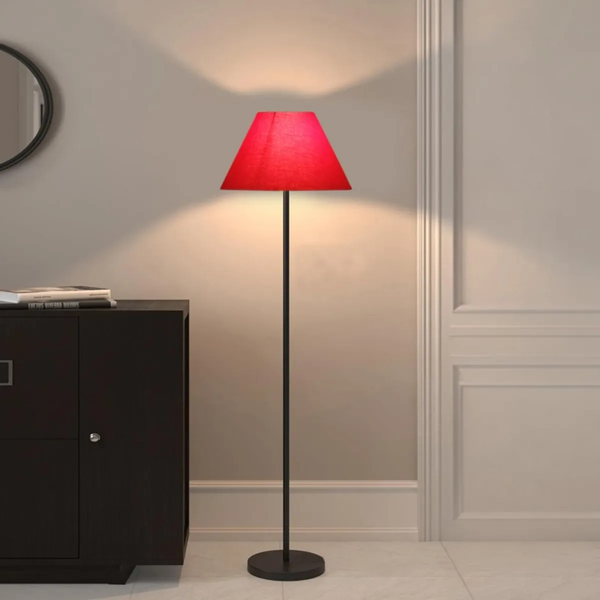 Red floor lamp lit against a pale wall beside a dark cabinet.