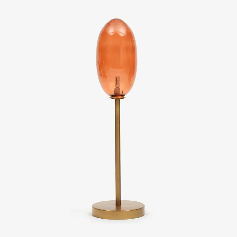 Amber glass table lamp with slim stand and round base on a plain background