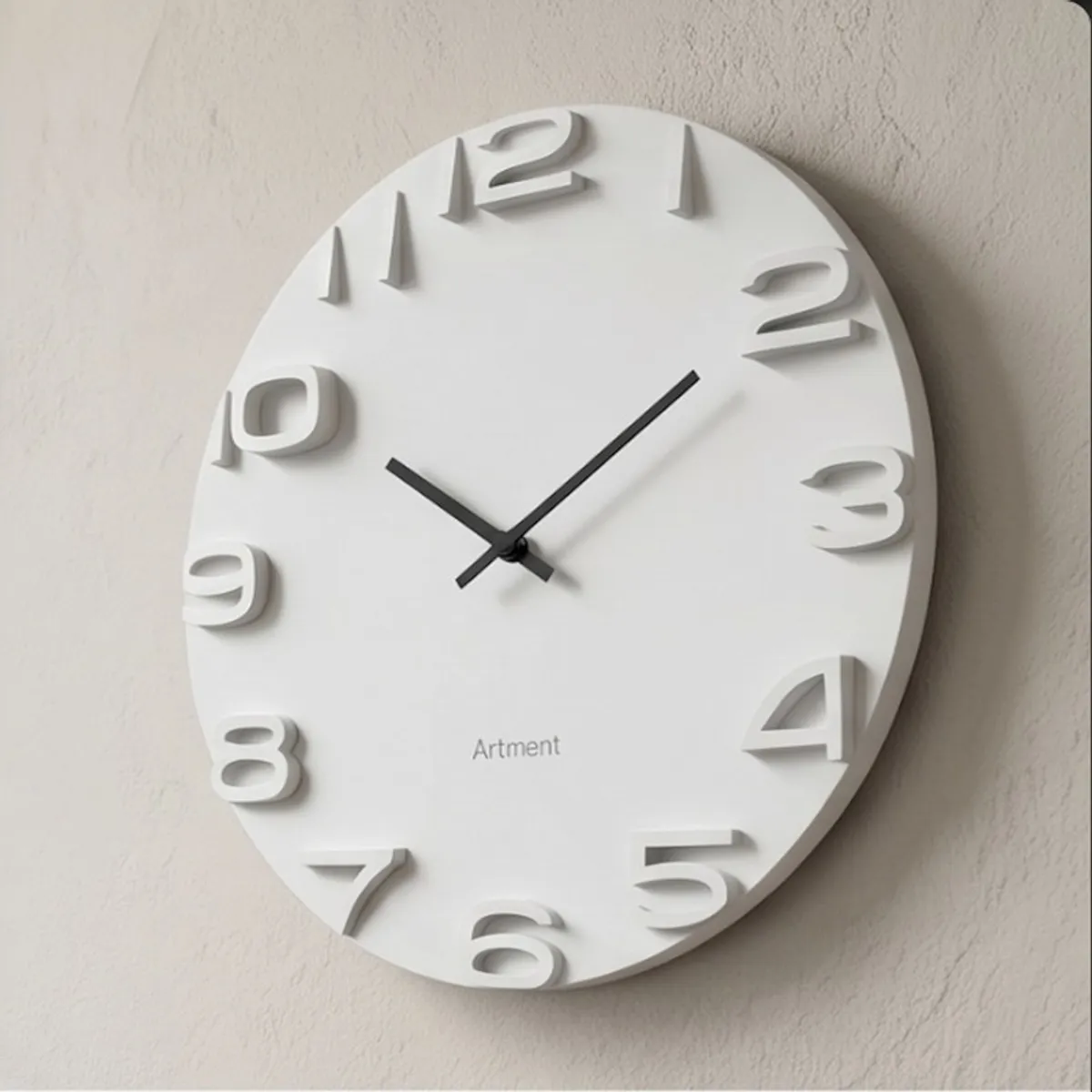 Angled view of a white round wall clock showing its raised dimensional numerals