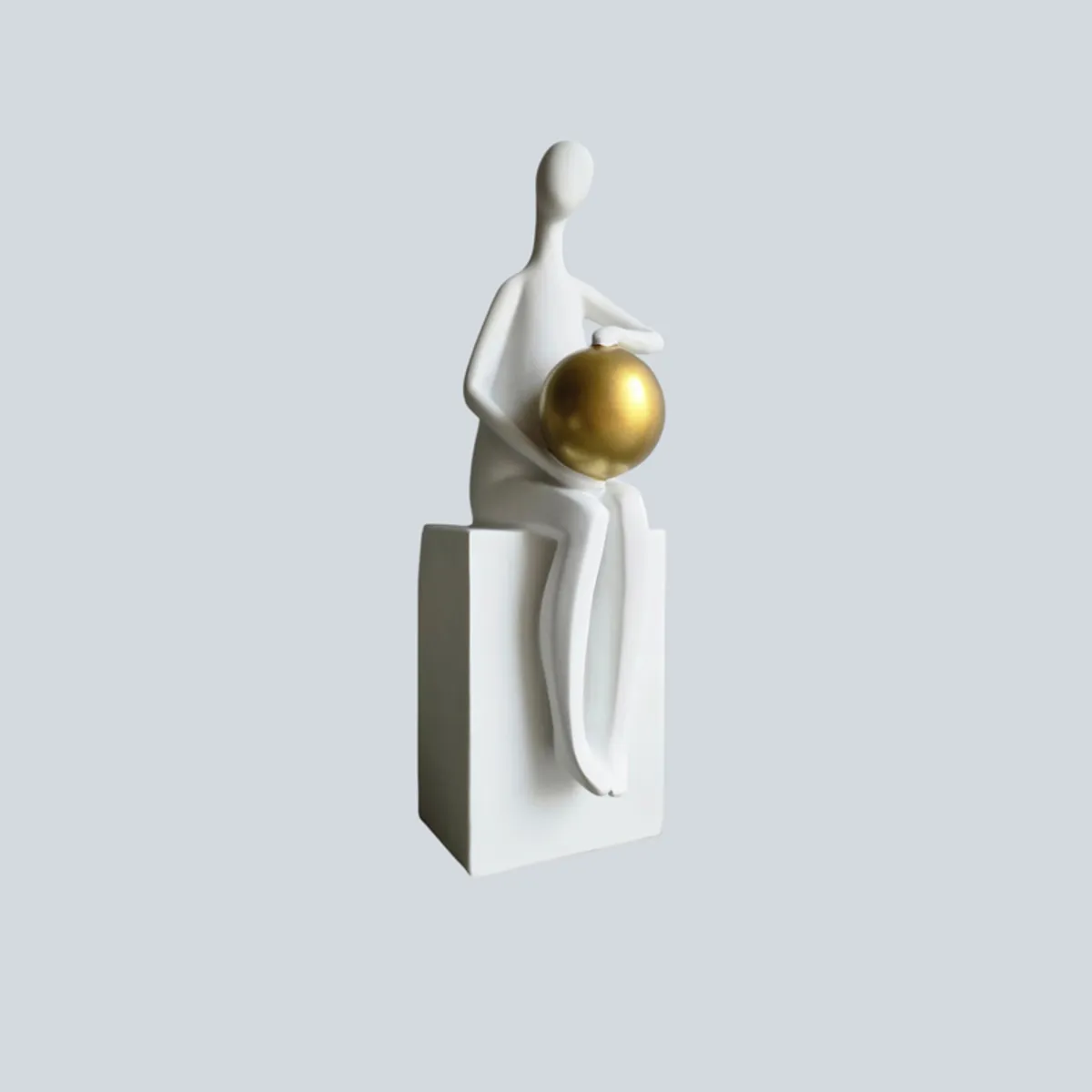 White abstract figurine with a gold sphere shown against a light background