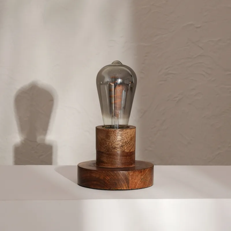 Unlit wooden table lamp with smoked glass bulb on a white ledge