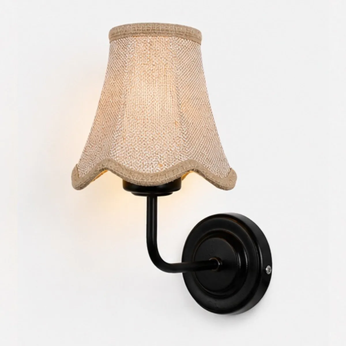 Close view of beige jute shade and black iron wall lamp base
