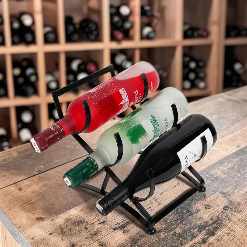 Black bottle holder with three wine bottles displayed on a wooden bar.