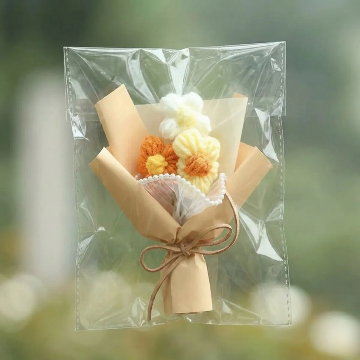 Beige-wrapped crochet flower arrangement shown inside a clear protective bag.