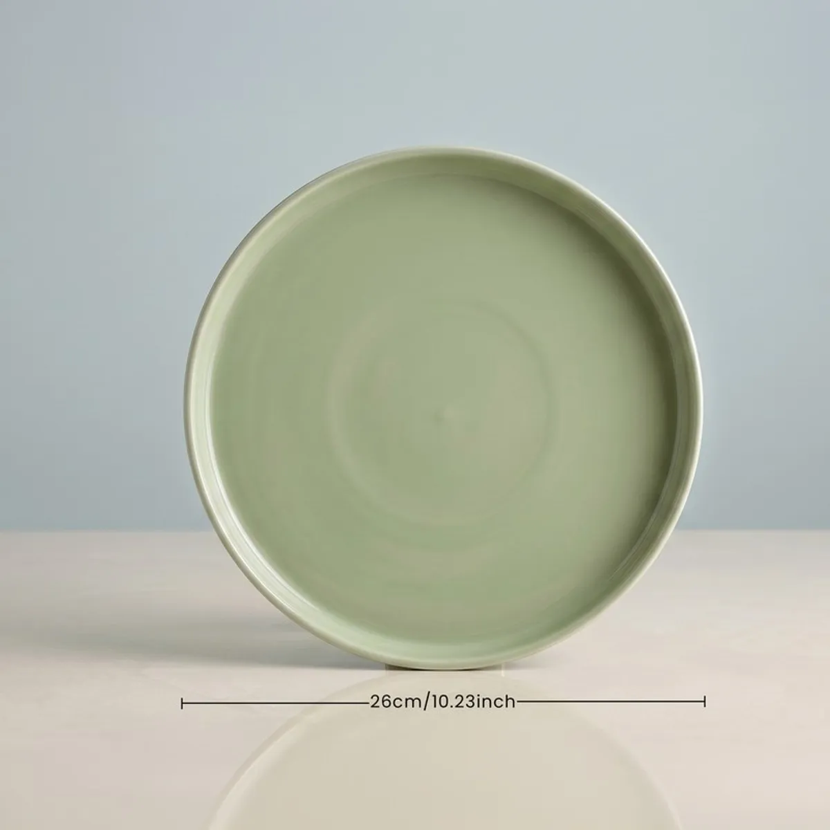 Front view of a sage green round dinner plate on a tabletop