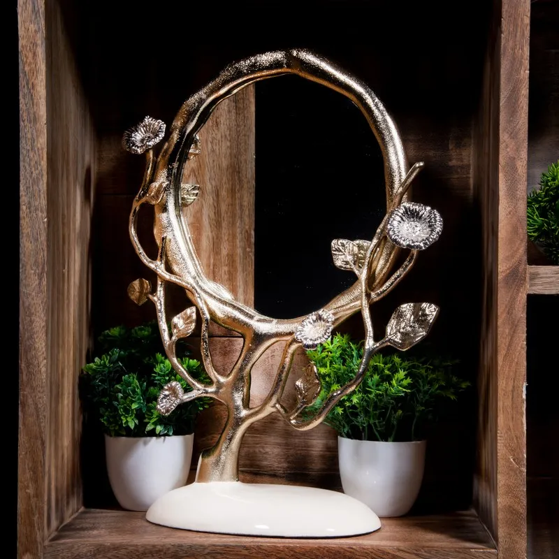 Floral round mirror with metallic branching frame displayed against a dark wooden backdrop.