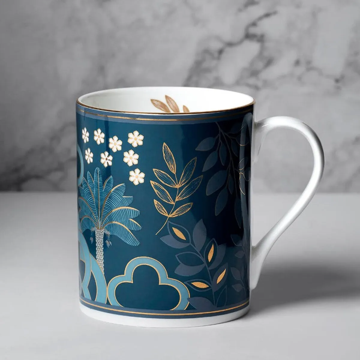 Close-up of a blue mug with floral and botanical motifs and a white handle.