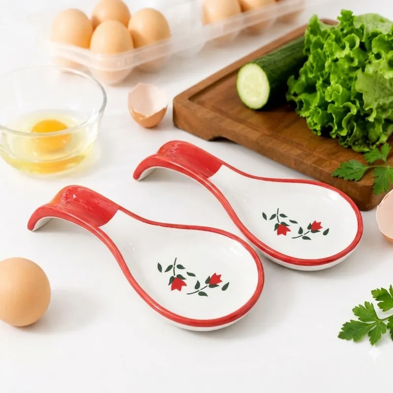 Two floral ceramic spoon rests styled beside eggs, vegetables and a chopping board
