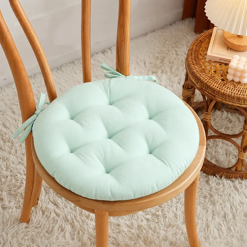 Sage green round chair pad tied onto a wooden dining chair