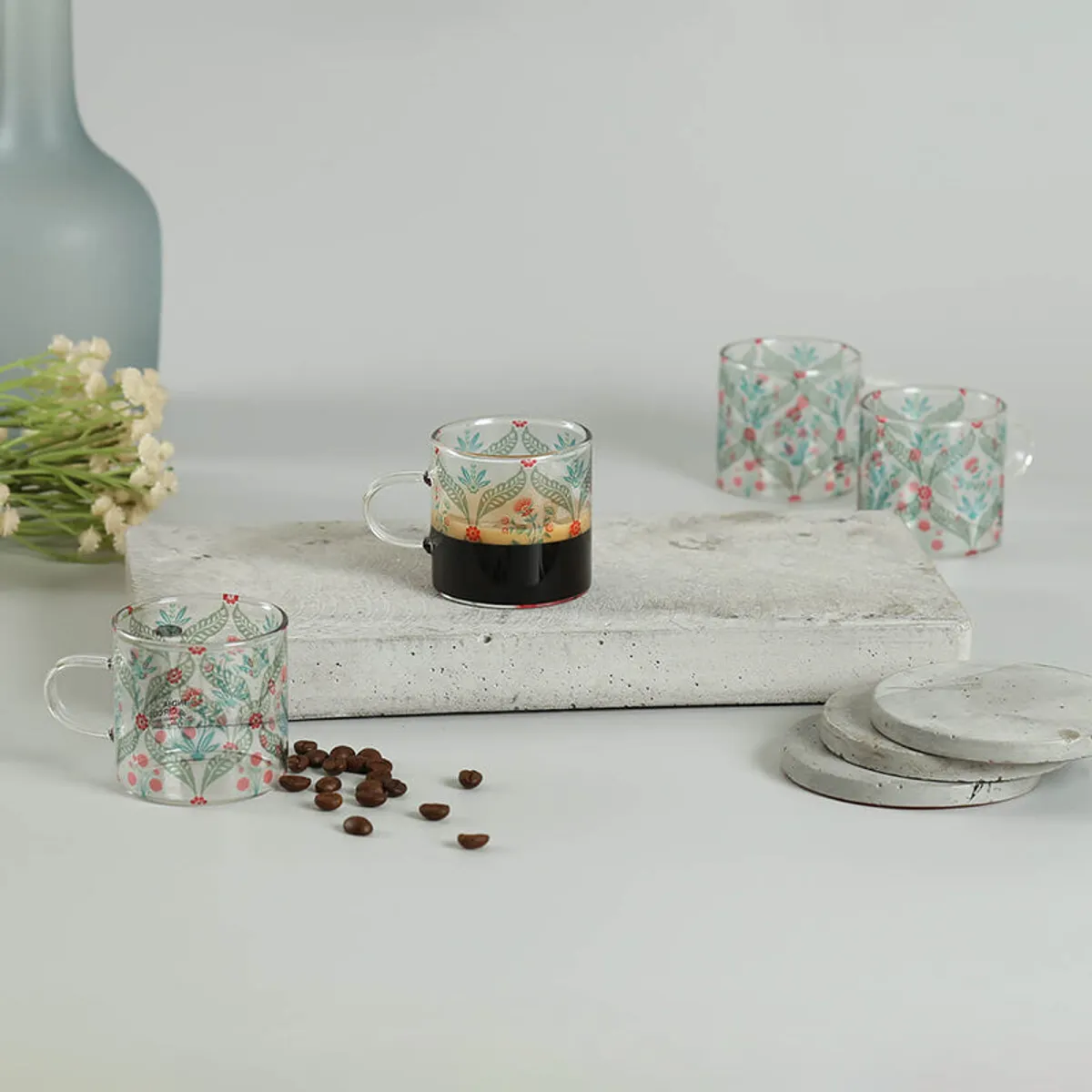 Floral glass mugs styled with coffee on a stone platform