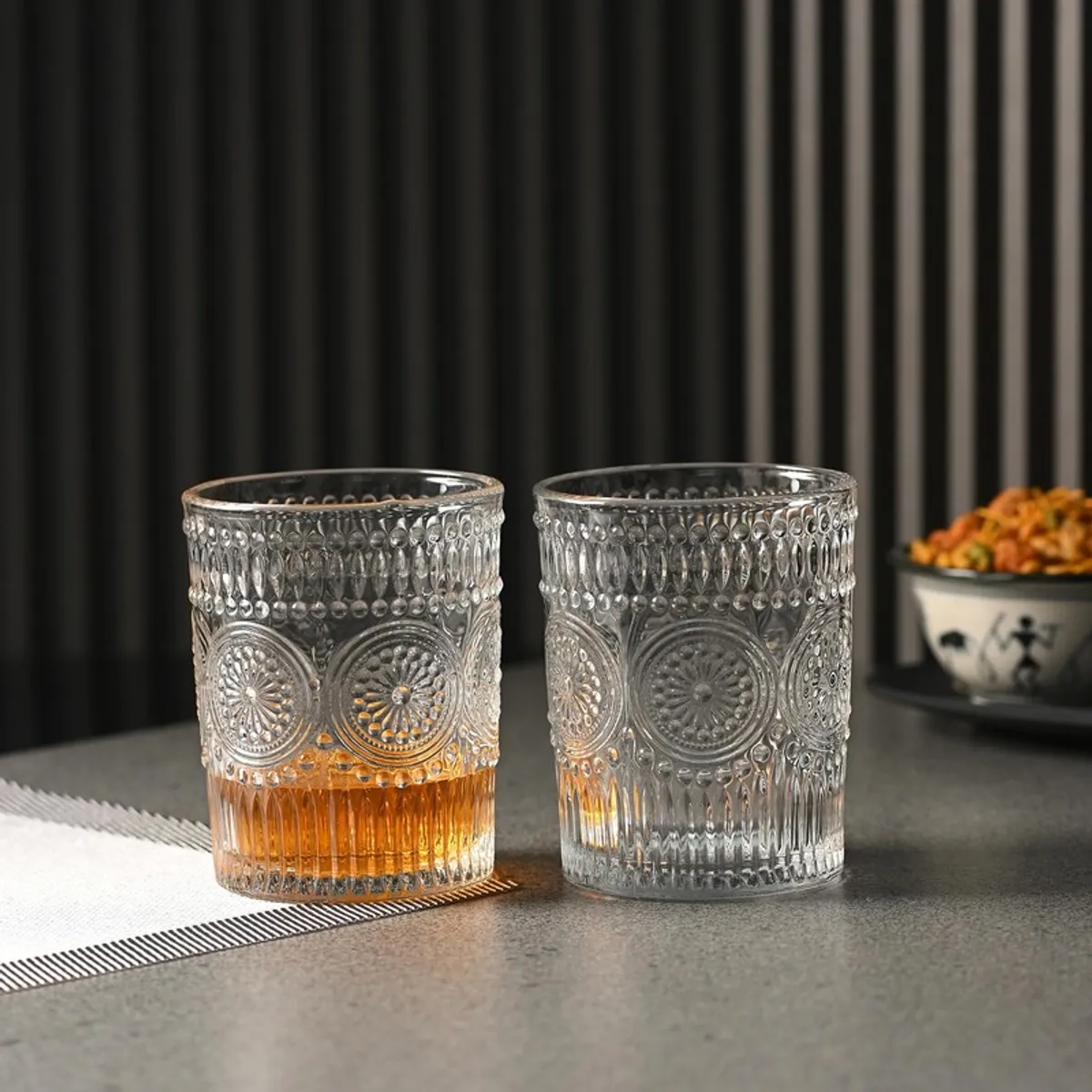 Two clear textured whiskey glasses on a tabletop