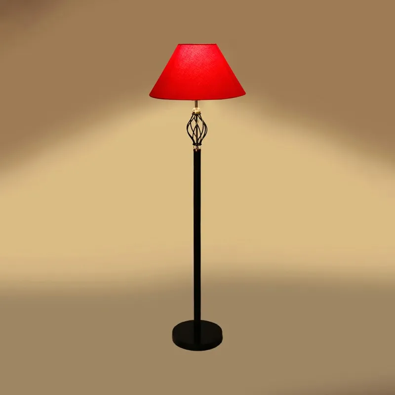 Red shade floor lamp with warm glow on a plain backdrop