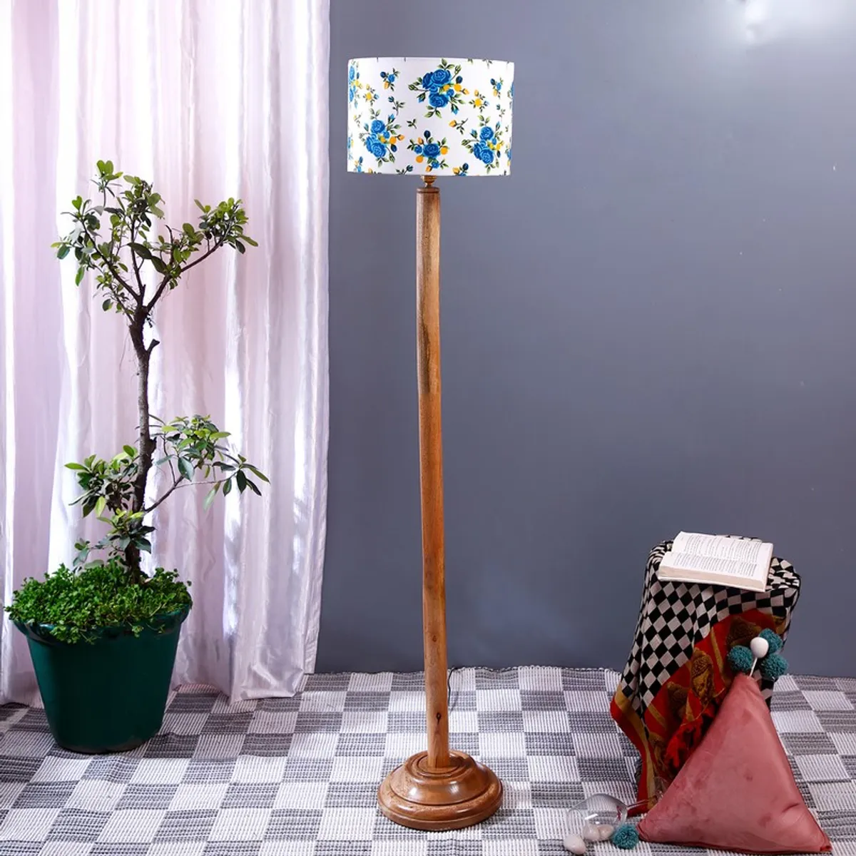 Wooden floor lamp with blue floral drum shade beside a potted plant and stool