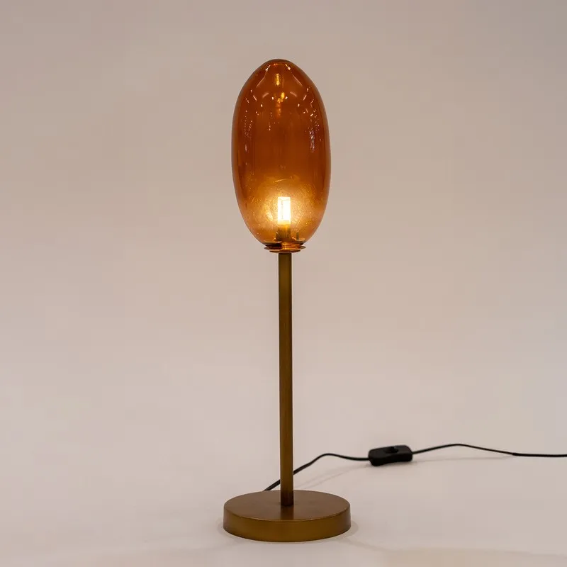 Amber glass table lamp with oval shade and round base on a plain background