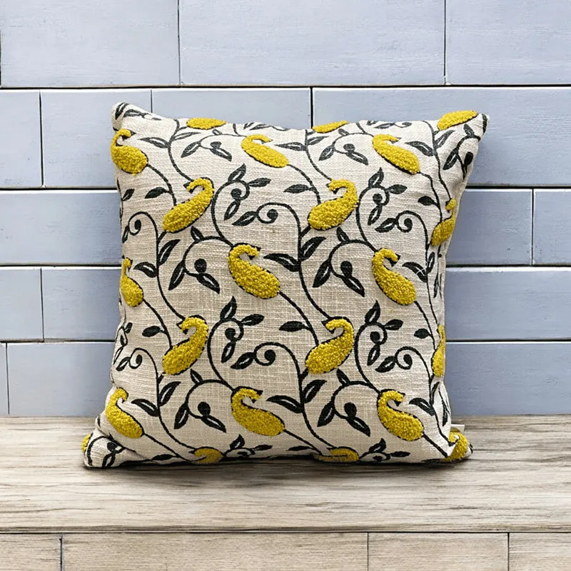 Yellow and black paisley cushion cover displayed against a pale blue tiled wall.