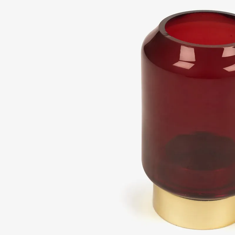 Partial side view of ruby red glass candle holder with gold base