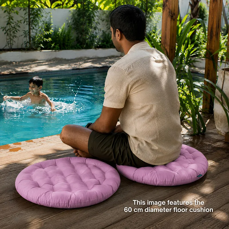 Person seated on a round lilac floor cushion beside a pool, with another cushion nearby.